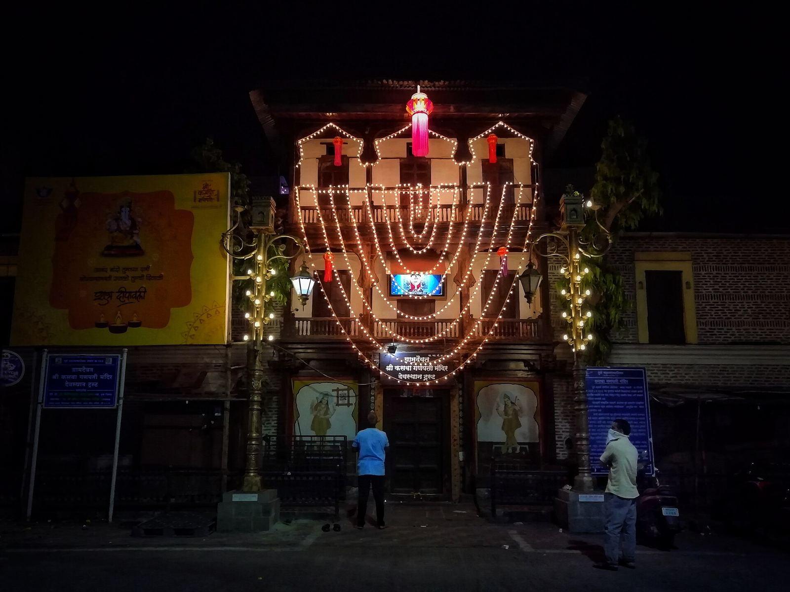Stone shikhara and pillared hall of Shri Kasba Ganpati temple in Kasba Peth, Pune, with a red flag on the spire
