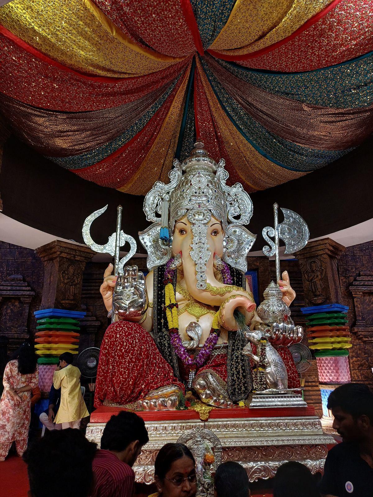 Festival idol of Tulshibaug Ganpati, crowned and seated, with blue and gold decoration